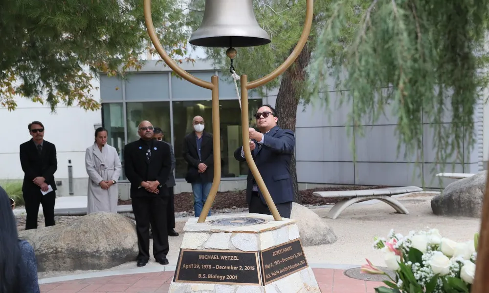Michael Nguyen, a former faculty member, rings the bell at the Peace Garden on the Day of Remembrance, Dec. 2.